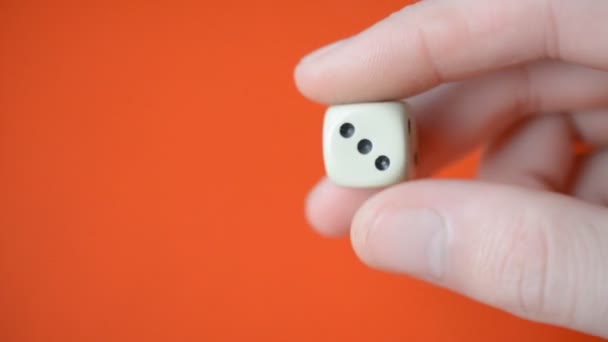 Dice in male fingers closeup on red background — Stock Video