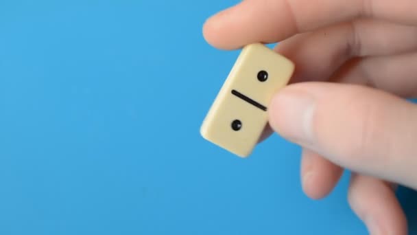 파란 배경에 있는 남성의 손가락에 도미노 칩 — 비디오