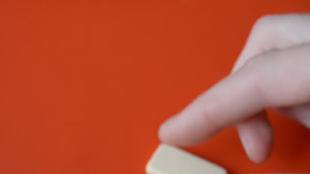 Dominostenen chips in mannelijke vingers op rode achtergrond — Stockvideo