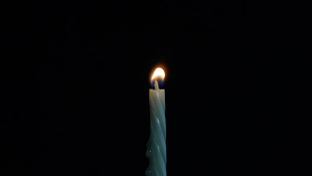 Vela branca isolada queimando em um fundo escuro — Vídeo de Stock