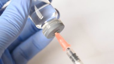 Doktor, mavi eldivenli ve şırıngalı eller laboratuardaki hastalara aşı yapılıyor.