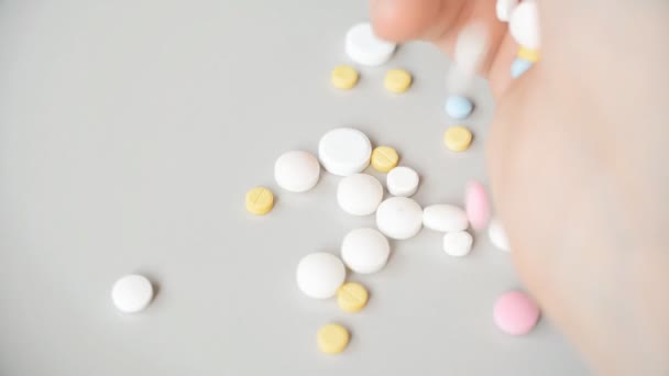 Různé barvy pilulky padající na šedé pozadí — Stock video