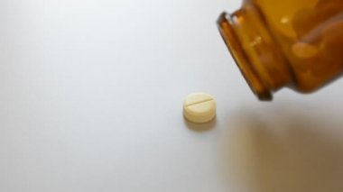 Yellow painkiller pills falling from glass bottle on a table