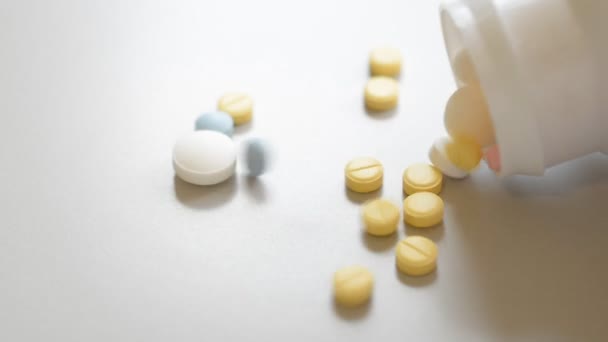 Pilules colorées d'antidépresseurs tombant d'une petite bouteille blanche gros plan 