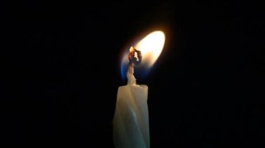 small candle burns on a black background