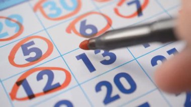 Signing a day on a calendar date 12, 13 by red pen