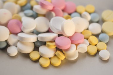 Baş ağrısı ve diş ağrısı hapları yakın plan gri arka planda.