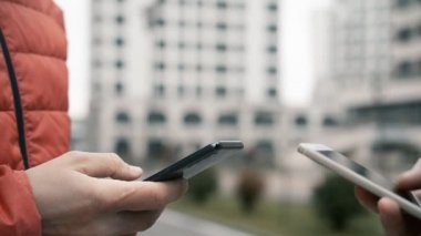Teenager hands using smartphone over modern buildings