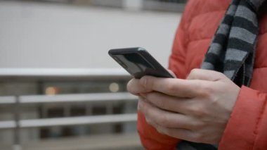 A man writes a texting SMS message using a smartphone outdoors
