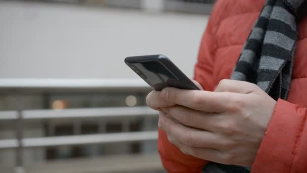 A man writes a texting SMS message using a smartphone outdoors — Wideo stockowe