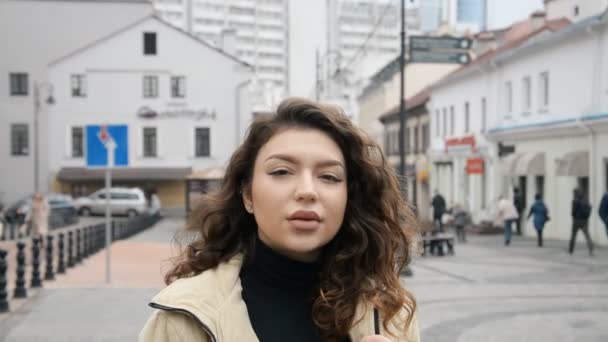 도시의 거리에서 찍은 아름다운 갈색 머리 소녀의 사진 — 비디오