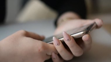 Akıllı telefon kullanan pembe mailli bir kadın.