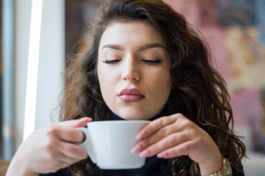 Kafede kahve içen güzel bir kızın portresi.