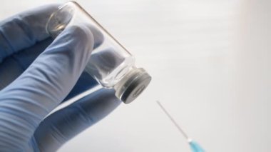 Doktorlar mavi eldiven ve koronovirüs aşısı hazırlıyor.