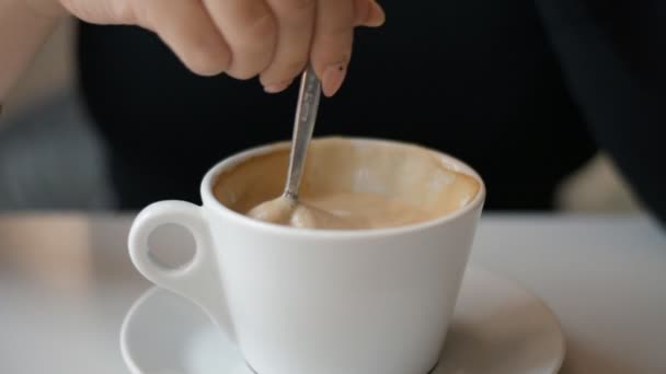 Close-up of cappuccino coffee cup stirred with spoon — Stock Video