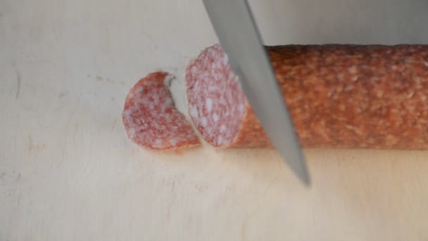 Close up shot of a man hands cutting thin slices of salami on a wooden board — Stock Video