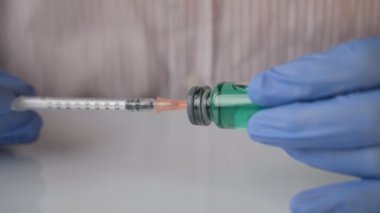 Mavi eldivenli doktor şırıngaya ilaç koyup iğneye hazırlıyor.