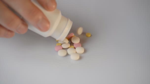 Pastillas de color para bajar la temperatura y tratar la gripe dormir lo suficiente de un frasco blanco sobre un fondo blanco — Vídeo de stock