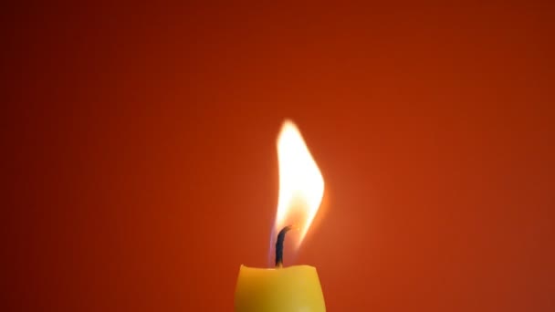 Plamen svíčky zblízka na červeném pozadí — Stock video