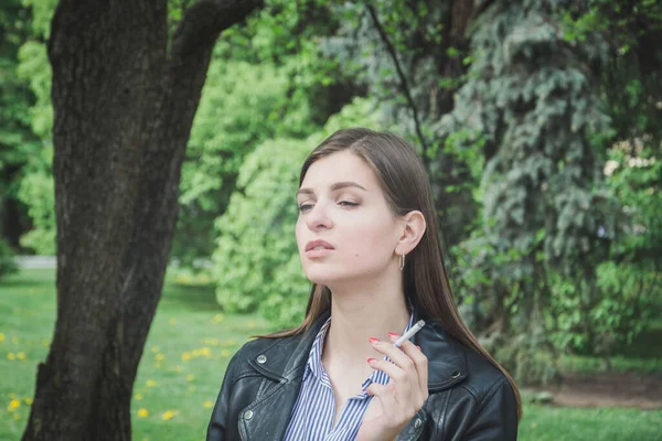 공원에 앉아서 담배를 피우는 소녀의 — 스톡 사진