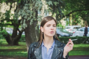 Genç kız parkta sigara içiyor, yaşam tarzı konsepti.