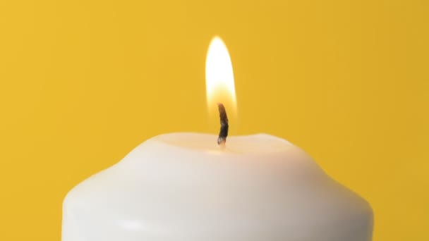 Белое пламя свечи на желтом фоне — стоковое видео