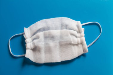 Mavi arka planda Coronavirus COVID-19 'a karşı korunmak için ev yapımı yüz maskesi.