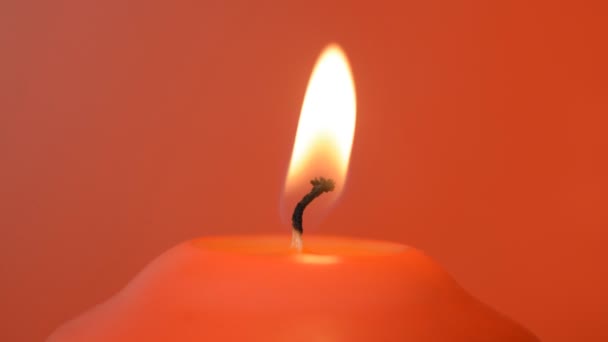 Красная свеча горит на красном фоне — стоковое видео