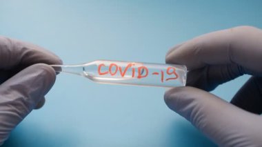 Ampulün virüse karşı bir aşısı var. COVID-19 bir doktorun elinde.
