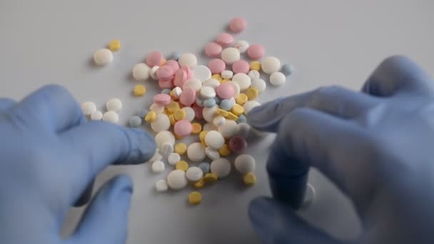 El hombre puso algunas píldoras médicas de colores en la mesa blanca. . — Vídeo de stock