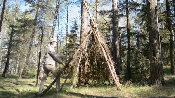 Чоловік у лісі будує хатину з сухих гілок, щоб зачекати пандемію коронавірусу — стокове відео
