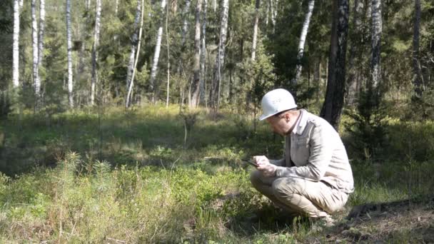 Δασολόγος μελετά ένα φυτό στο δάσος και γράφει δεδομένα στην ταμπλέτα — Αρχείο Βίντεο