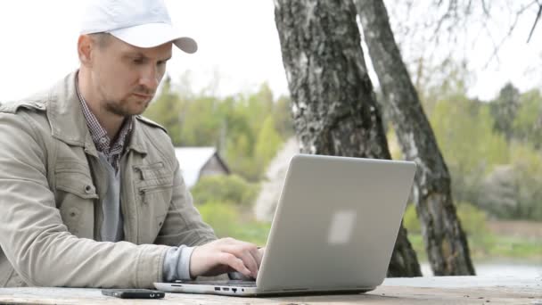 Empresário caucasiano trabalha em laptop contra floresta — Vídeo de Stock