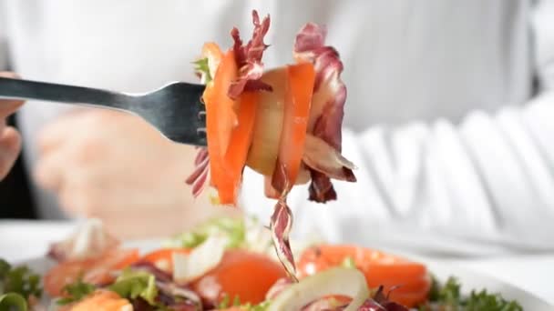 Человек смешивает элементы салата с серебряной вилкой — стоковое видео