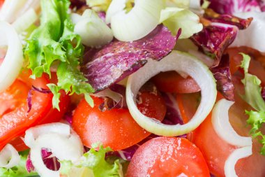 Domatesli taze vejetaryen salatası soğan ve yeşil yapraklar yakın plan.
