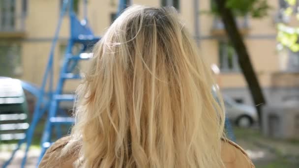 Blont hår kvinnligt huvud tillbaka vy utomhus — Stockvideo