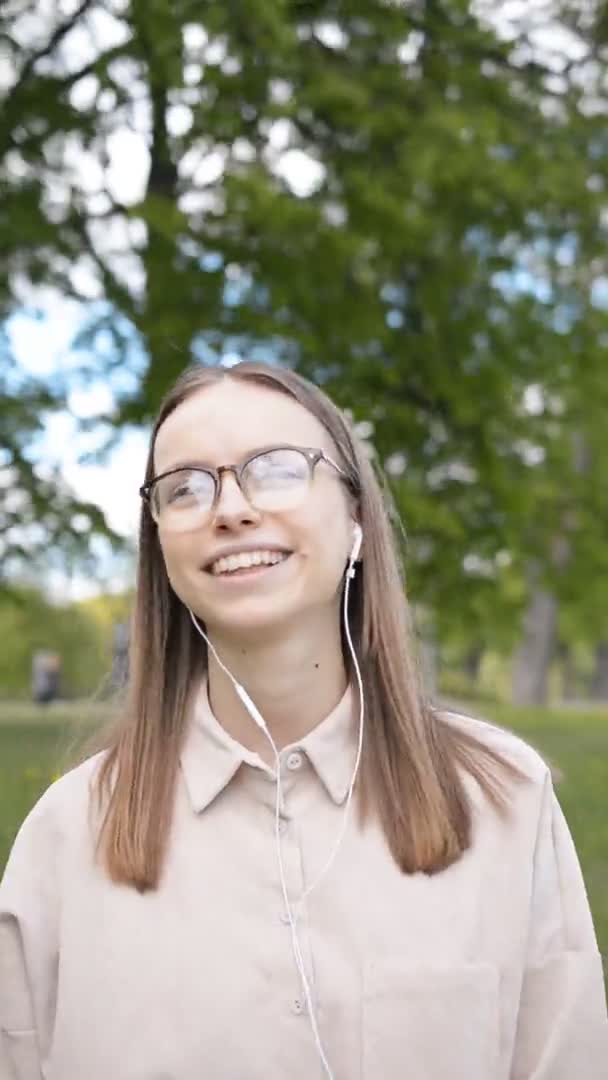 Молодая кавказская девушка в наушниках слушает музыку и поет любимые песни — стоковое видео