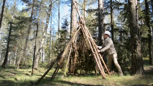 Vit man gör ett skydd i skogen — Stockvideo