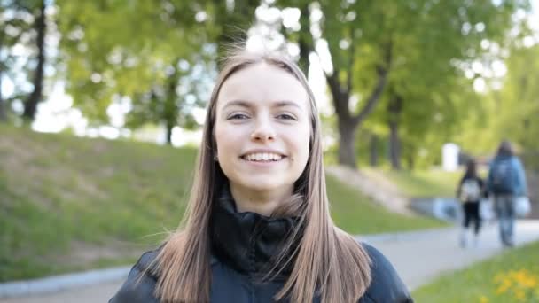 Кавказка красивая женщина смотрит в камеру, улыбается и смеется на улице — стоковое видео
