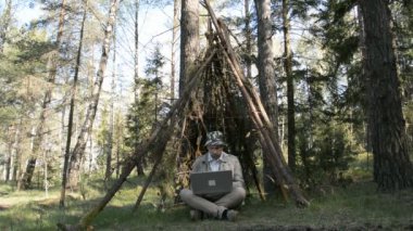 Serbest programcı insanlardan ormanda saklanıyor ve dizüstü bilgisayarında tek başına çalışıyor.