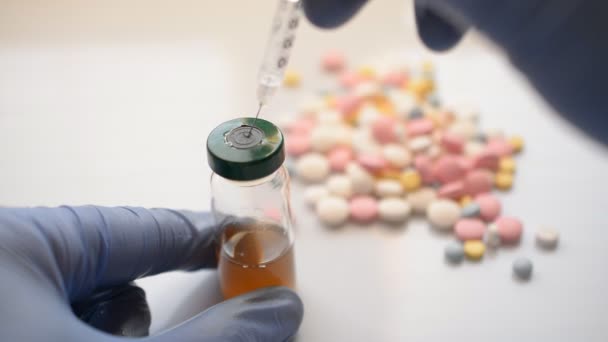 Mano de los médicos sostiene una jeringa y un frasco de vacuna marrón en la mesa del médico en el hospital — Vídeos de Stock