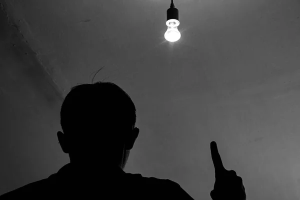 A man and a light bulb, a silhouette of a man under a light bulb.