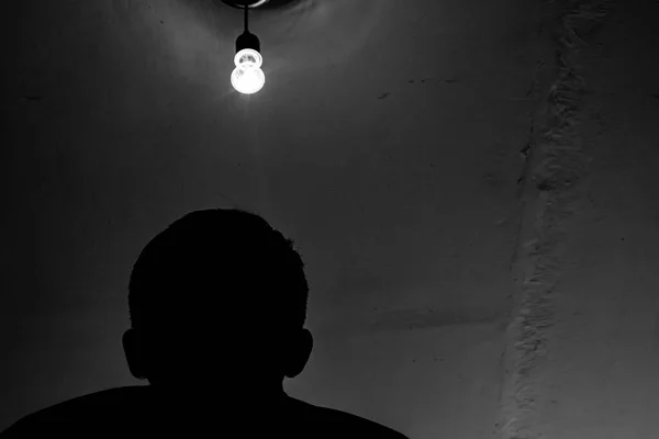 A man and a light bulb, a silhouette of a man under a light bulb.