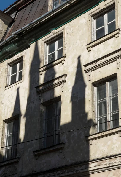 Riga, Latvia. Shabby wall of a house in the Old Town area. The shadows of several towers fall on the wall of this house. Sunset