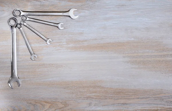 Shiny metal keys are laid out in the upper left corner of a wooden vintage tabletop and form a thematic frame for placing text on the theme of Labor Day