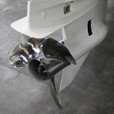 Teknenin dış motoru, su altı, alt ünite, yakın çekim, beyaz vites kutusu, merkezinde paslanmaz çelik pervane var.