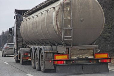 Büyük kirli varil yarı yakıt tankeri. Bahar gününde banliyö otobanının arka tarafında, orman arka planında, uzun araç sıvı kargo taşımacılığı.