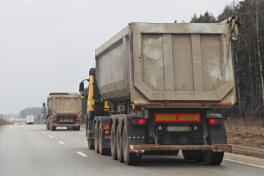 İlkbahar günü asfaltlanmış otoyoldaki inşaat sahasında gri ağır damperli kamyon sürücüsü. Arka taraf lojistiği, toplu kargo taşımacılığı.