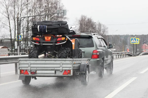 Driving safety on a wet slippery road with a single-axle trailer  SUV car fast carries a Quad bike after rain, aquaplaning dangerous