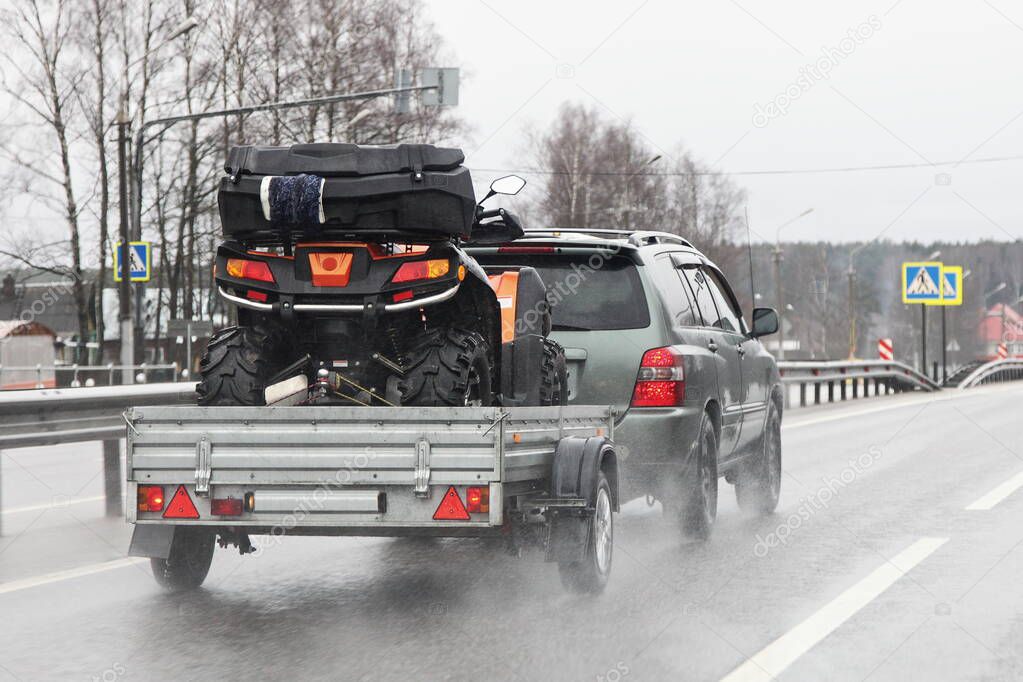 Driving safety on a wet slippery road with a single-axle trailer  SUV car fast carries a Quad bike after rain, aquaplaning dangerous